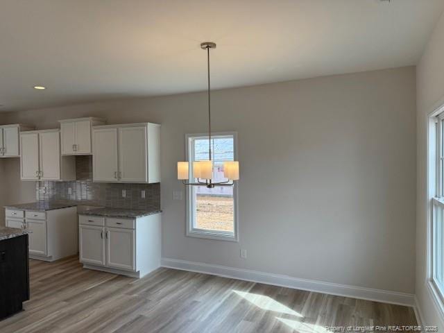 kitchen featuring light wood-type flooring, baseboards, decorative backsplash, and white cabinets