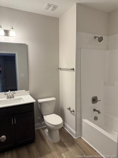 bathroom with toilet, wood finished floors, vanity, visible vents, and baseboards