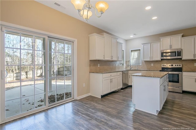 kitchen with pendant lighting, white cabinetry, stainless steel appliances, and a kitchen island