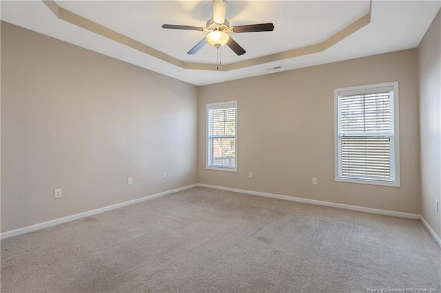 carpeted spare room featuring ceiling fan and a tray ceiling