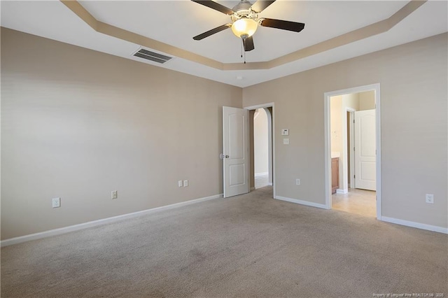 unfurnished room with light colored carpet, ceiling fan, and a tray ceiling