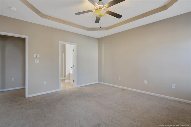 carpeted spare room with ceiling fan and a tray ceiling