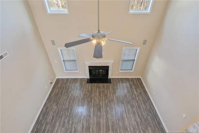 unfurnished living room with dark wood-type flooring, a premium fireplace, and a high ceiling