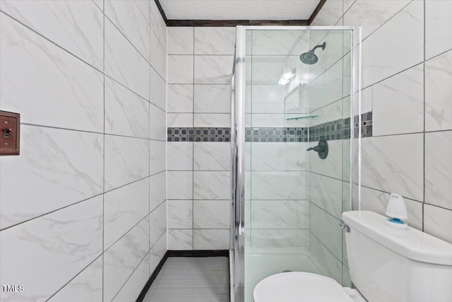 bathroom featuring tile walls, an enclosed shower, a textured ceiling, and toilet