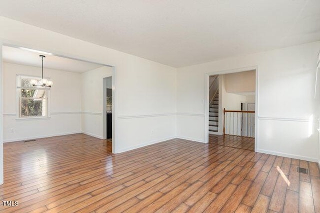 empty room featuring hardwood / wood-style floors and a chandelier