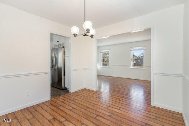 unfurnished dining area with an inviting chandelier and dark hardwood / wood-style floors