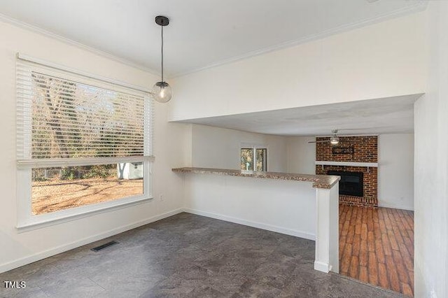 kitchen with crown molding, a brick fireplace, decorative light fixtures, and kitchen peninsula