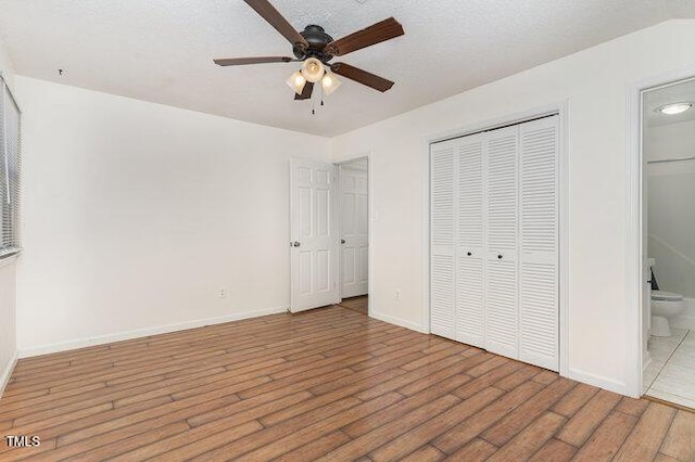 unfurnished bedroom with hardwood / wood-style flooring, ceiling fan, connected bathroom, a textured ceiling, and a closet