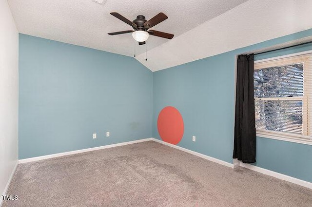 spare room featuring vaulted ceiling, carpet floors, ceiling fan, and a textured ceiling