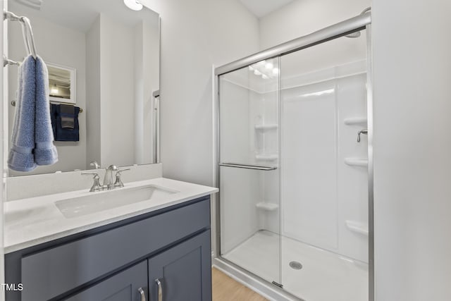 bathroom with hardwood / wood-style flooring, vanity, and a shower with shower door