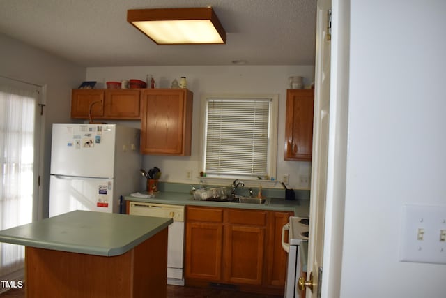 kitchen with sink, white appliances, a textured ceiling, and a kitchen island