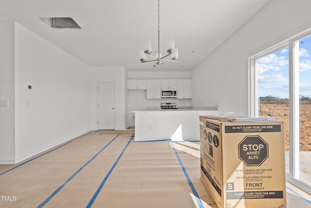 kitchen with hanging light fixtures, a chandelier, white cabinets, and appliances with stainless steel finishes