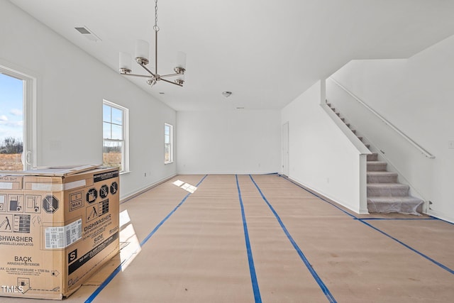 unfurnished living room featuring a chandelier