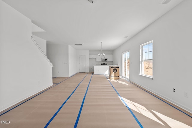 unfurnished living room with an inviting chandelier and light hardwood / wood-style flooring