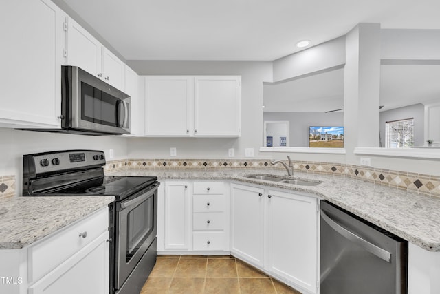 kitchen featuring appliances with stainless steel finishes, white cabinetry, sink, light tile patterned floors, and light stone counters