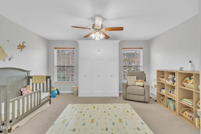 bedroom with ceiling fan, light colored carpet, and a crib