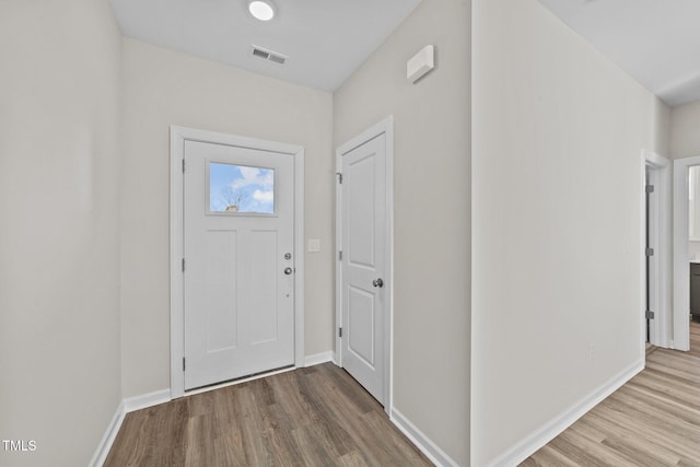 foyer entrance featuring visible vents, baseboards, and wood finished floors