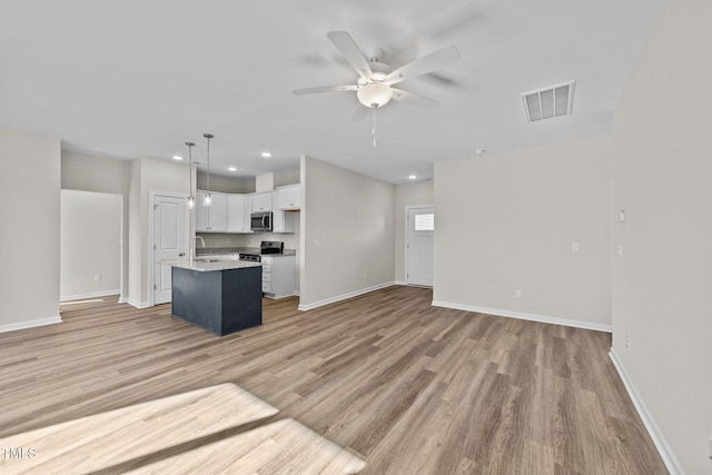 kitchen with white cabinetry, light hardwood / wood-style flooring, pendant lighting, ceiling fan, and a kitchen island with sink