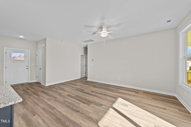 unfurnished living room with hardwood / wood-style flooring, a wealth of natural light, and ceiling fan