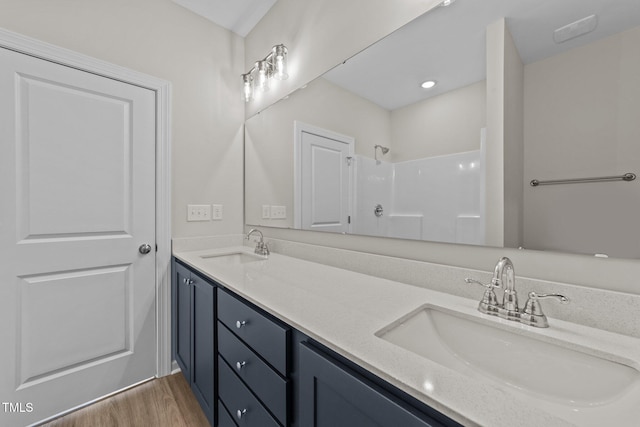 bathroom with wood-type flooring, vanity, and a shower