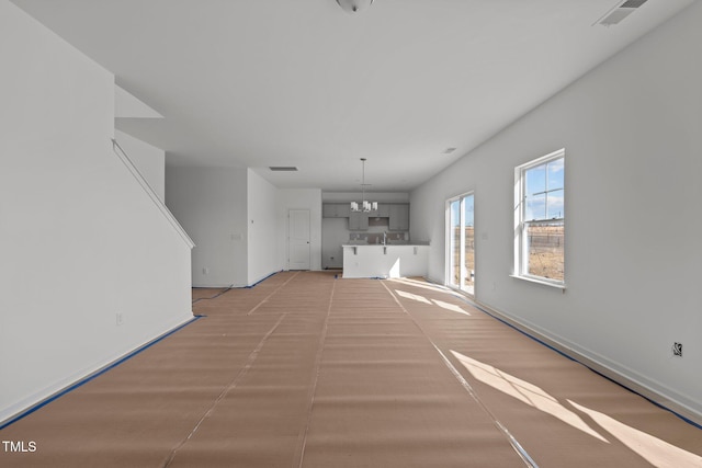 unfurnished living room featuring an inviting chandelier