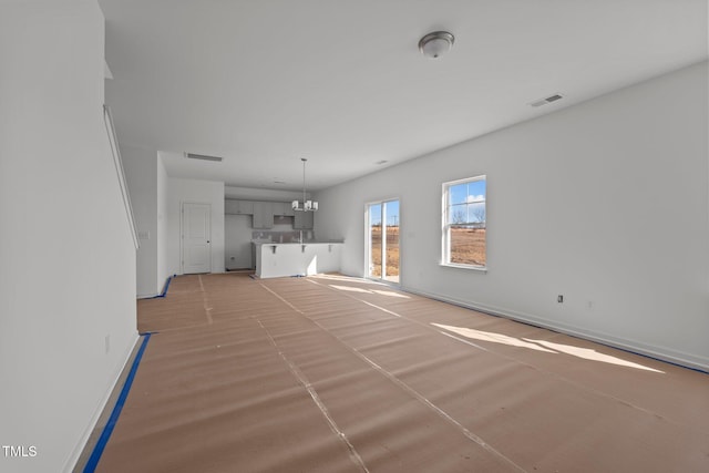 unfurnished living room with a notable chandelier