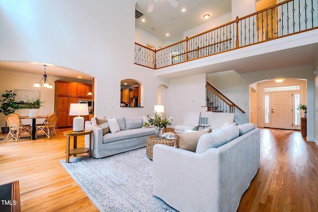 living room featuring ornamental molding, a towering ceiling, and light wood-type flooring