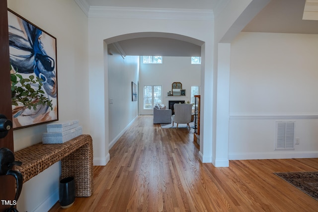 hall with ornamental molding and light hardwood / wood-style floors