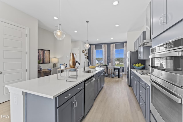 kitchen with gray cabinets, appliances with stainless steel finishes, sink, and a center island with sink