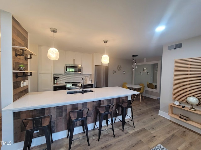 kitchen featuring pendant lighting, sink, stainless steel appliances, white cabinets, and kitchen peninsula