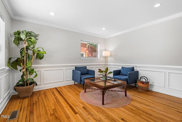 sitting room with crown molding and light hardwood / wood-style flooring