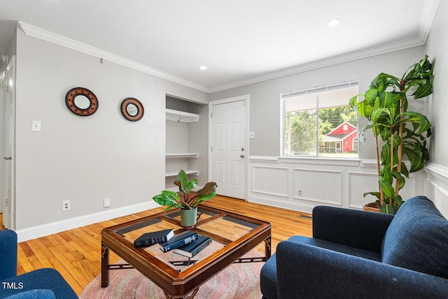 living room with crown molding, light hardwood / wood-style floors, and built in shelves