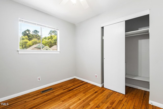 unfurnished bedroom with wood-type flooring, ceiling fan, and a closet