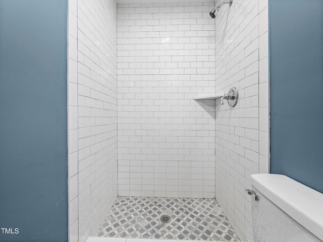 bathroom featuring a tile shower and toilet