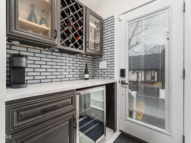 bar featuring wine cooler, light tile patterned floors, backsplash, and dark brown cabinets