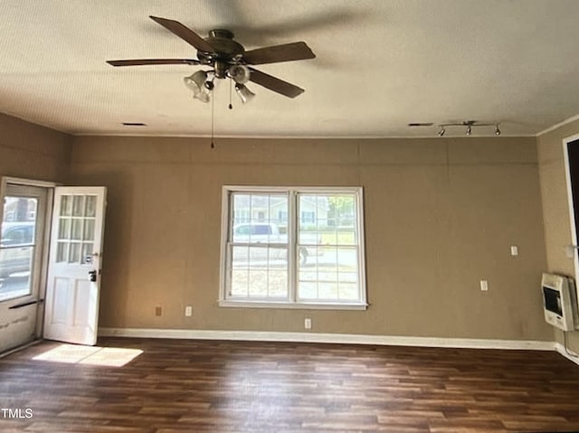 empty room featuring dark hardwood / wood-style floors, heating unit, a textured ceiling, and ceiling fan