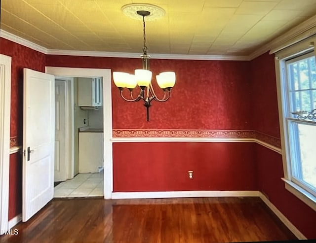 unfurnished dining area featuring an inviting chandelier, wood-type flooring, and ornamental molding