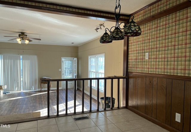 empty room with ceiling fan, light tile patterned floors, a textured ceiling, and wood walls