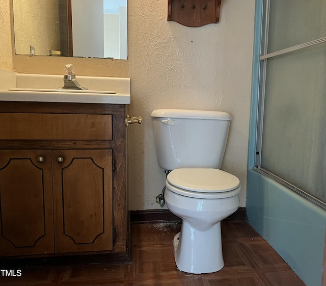 full bathroom featuring enclosed tub / shower combo, parquet floors, vanity, and toilet