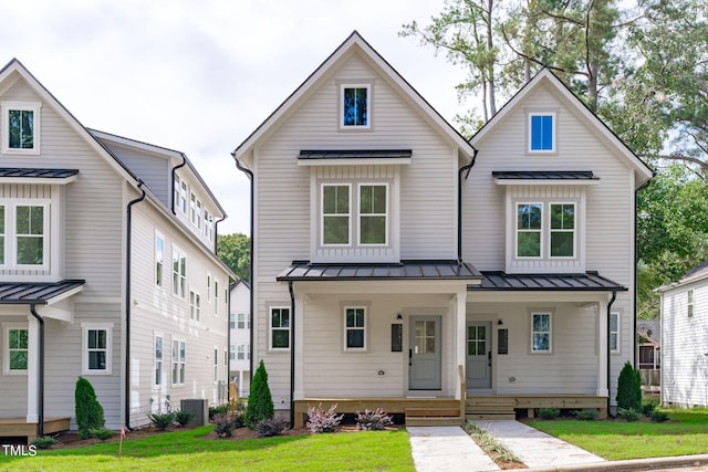 modern farmhouse with central AC unit, covered porch, and a front yard