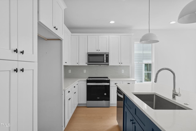 kitchen featuring pendant lighting, stainless steel appliances, and white cabinets