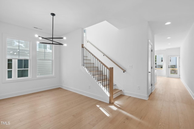 stairs with an inviting chandelier and wood-type flooring