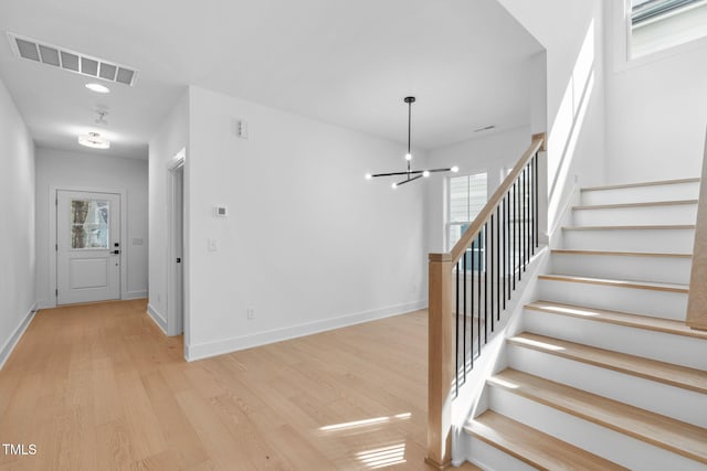 stairs featuring hardwood / wood-style flooring and a chandelier