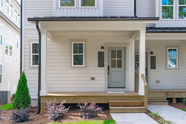 view of exterior entry with central AC and a porch