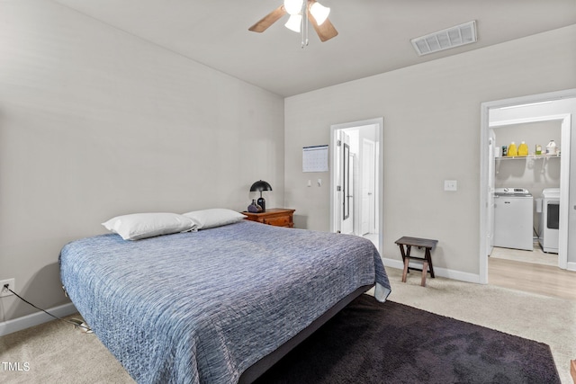 bedroom featuring ensuite bathroom, washer and dryer, light carpet, and ceiling fan