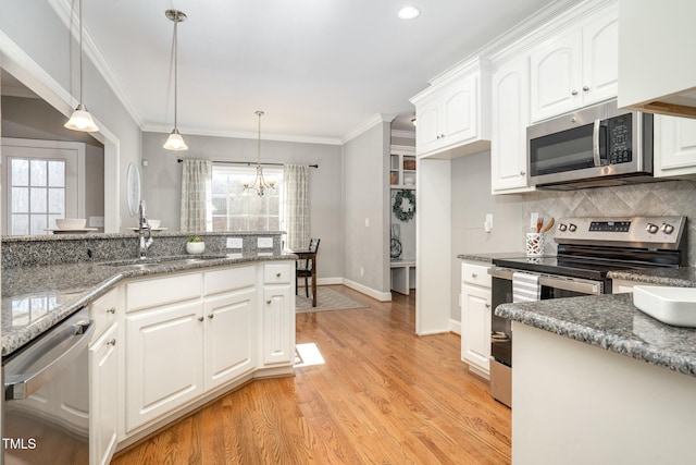 kitchen with white cabinetry, pendant lighting, stainless steel appliances, and dark stone counters