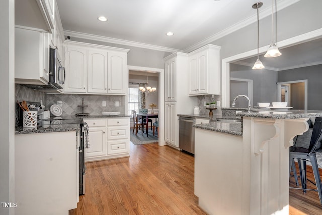 kitchen featuring white cabinetry, a kitchen bar, sink, and appliances with stainless steel finishes