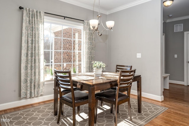 dining space featuring hardwood / wood-style flooring, ornamental molding, and an inviting chandelier