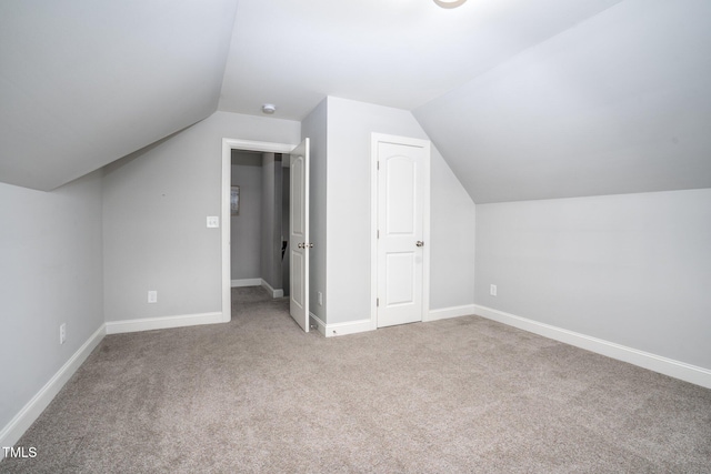 additional living space featuring lofted ceiling and carpet