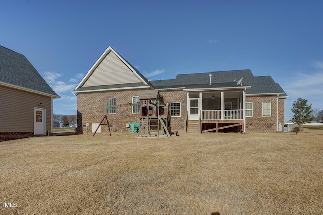 back of house featuring a playground, a sunroom, and a lawn